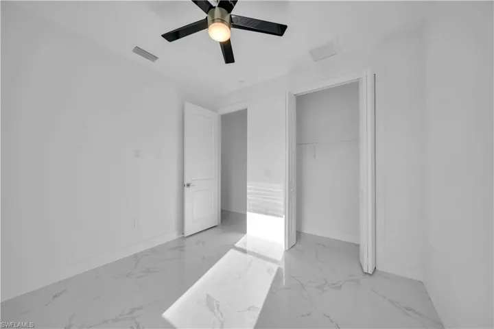 Unfurnished bedroom featuring a ceiling fan, a closet, and light marble finish floors