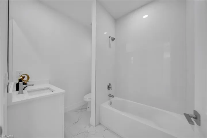 Full bath featuring vanity, tub / shower combination, and light marble finish flooring
