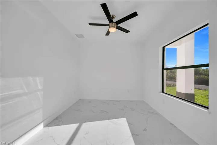 Unfurnished room featuring ceiling fan and light marble finish floors