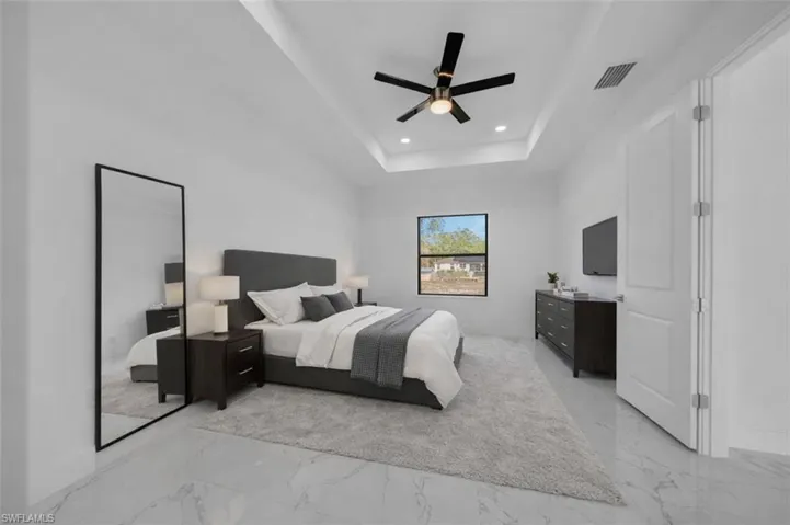 Bedroom featuring ceiling fan, light marble finish floors, recessed lighting, and a tray ceiling