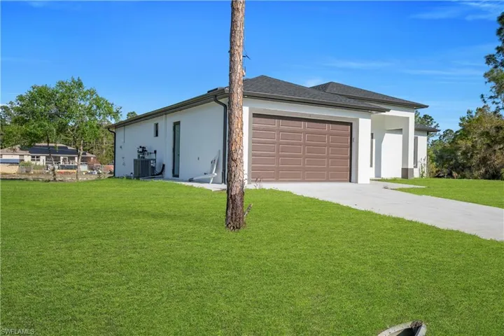 View of home's exterior with stucco siding, a lawn, a garage, and concrete driveway