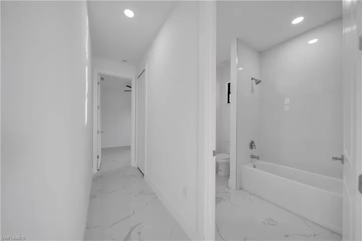Full bath with shower / bathtub combination, recessed lighting, and light marble finish floors