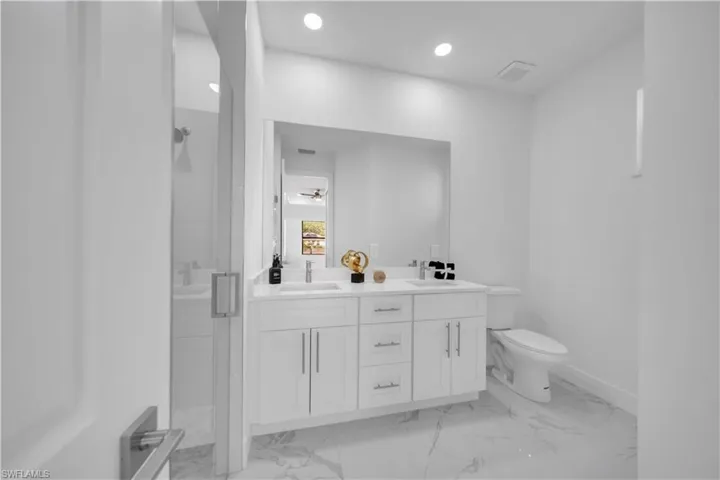 Bathroom featuring double vanity, a stall shower, recessed lighting, and light marble finish floors