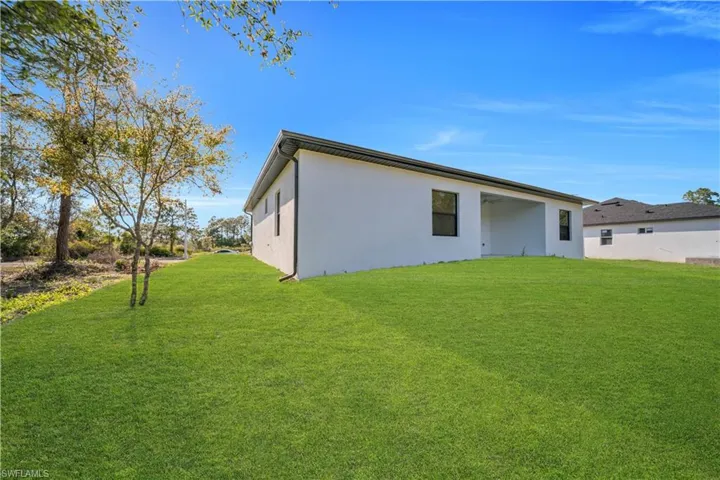 Back of property with a yard and stucco siding