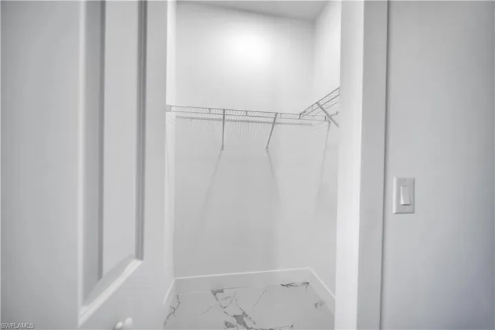 Walk in closet with light marble finish flooring