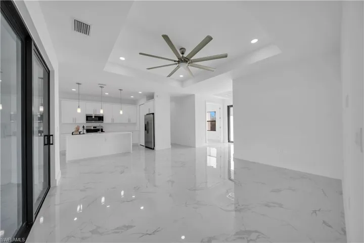 Unfurnished living room with recessed lighting, a ceiling fan, and a tray ceiling