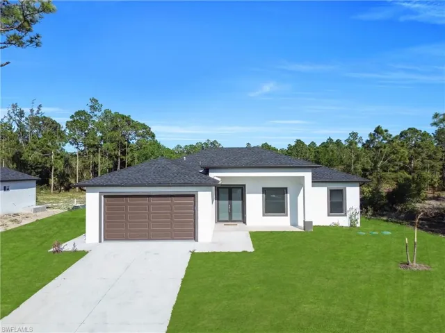 View of front facade featuring a front yard, concrete driveway, a shingled roof, and an attached garage