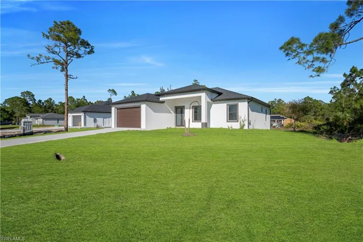 View of front of home featuring a front yard, stucco siding, driveway, and a garage