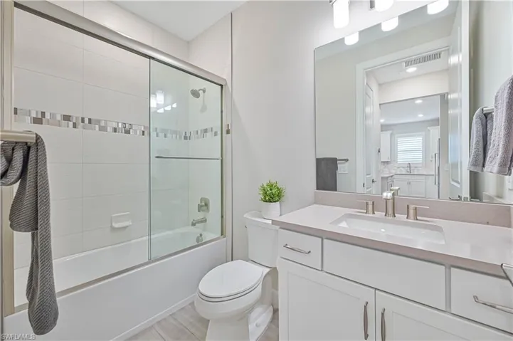 Full bathroom featuring bath / shower combo with glass door, vanity, and toilet