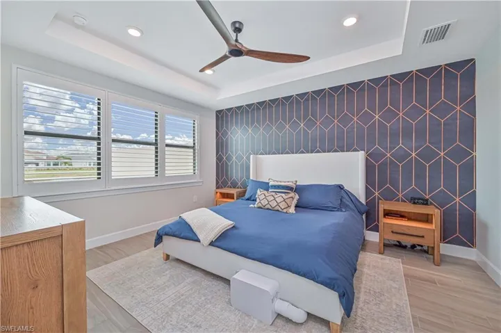 Bedroom with hardwood / wood-style flooring, ceiling fan, and a tray ceiling