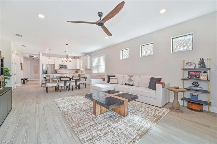 Living room featuring ceiling fan with notable chandelier and light hardwood / wood-style flooring