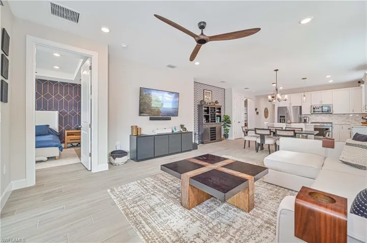 Living room featuring ceiling fan with notable chandelier