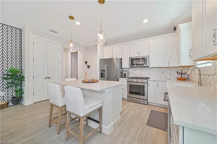 Kitchen featuring pendant lighting, sink, white cabinets, premium appliances, and a center island