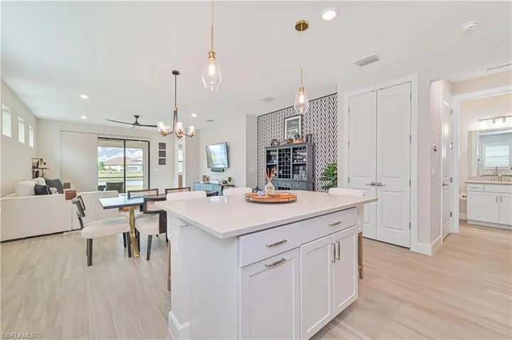 Kitchen featuring light hardwood / wood-style flooring, a center island, white cabinets, decorative light fixtures, and a chandelier