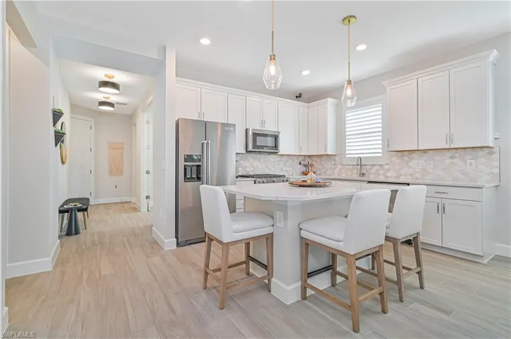 Kitchen with appliances with stainless steel finishes, white cabinets, and backsplash