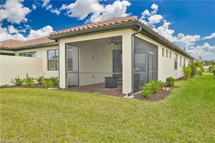 Rear view of property with a yard, a sunroom, a patio, and ceiling fan
