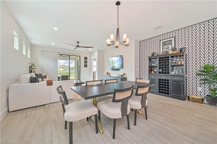 Dining space featuring ceiling fan with notable chandelier and light hardwood / wood-style flooring