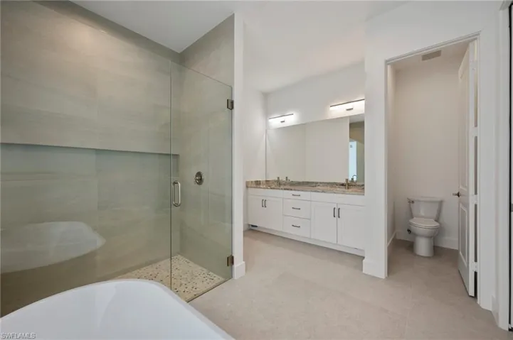 Bathroom with a shower stall, double vanity, and a soaking tub