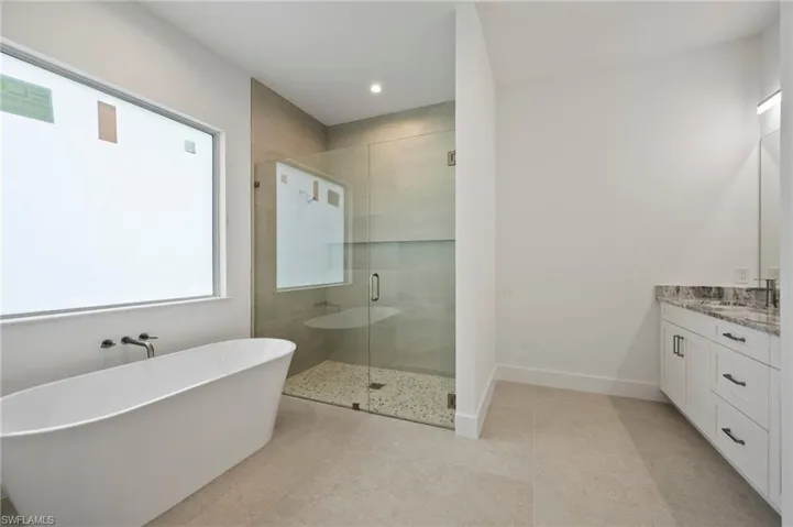 Full bathroom with a shower stall, vanity, a freestanding bath, and recessed lighting
