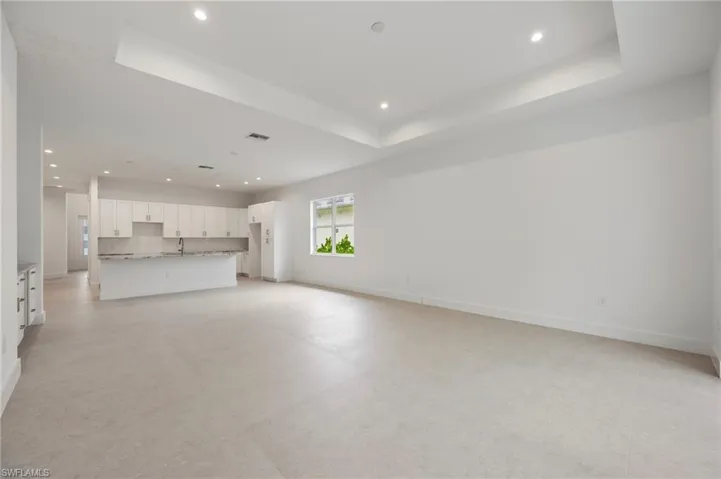 Unfurnished living room with recessed lighting, a tray ceiling, and light flooring