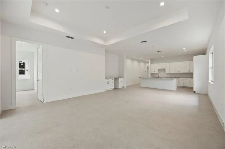 Unfurnished living room featuring recessed lighting and a tray ceiling