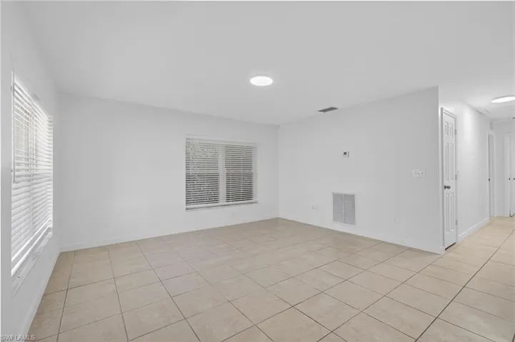 Empty room featuring light tile patterned flooring and attic access