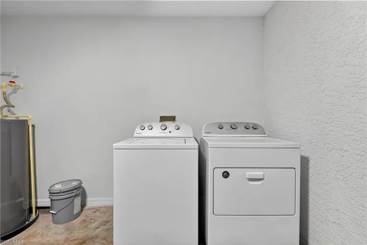 Washroom featuring water heater and washer and clothes dryer