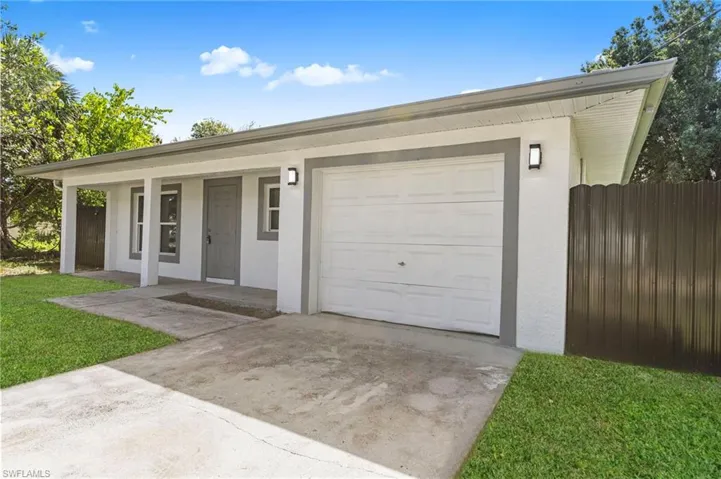 Single story home with concrete driveway, a porch, and stucco siding