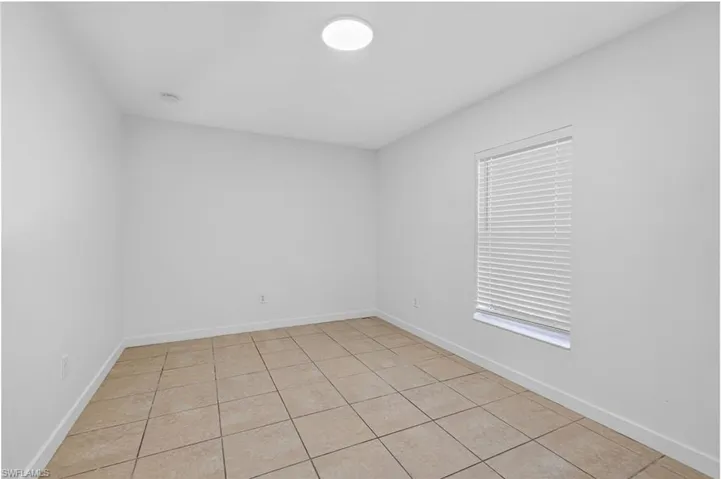 Unfurnished room with light tile patterned floors and baseboards