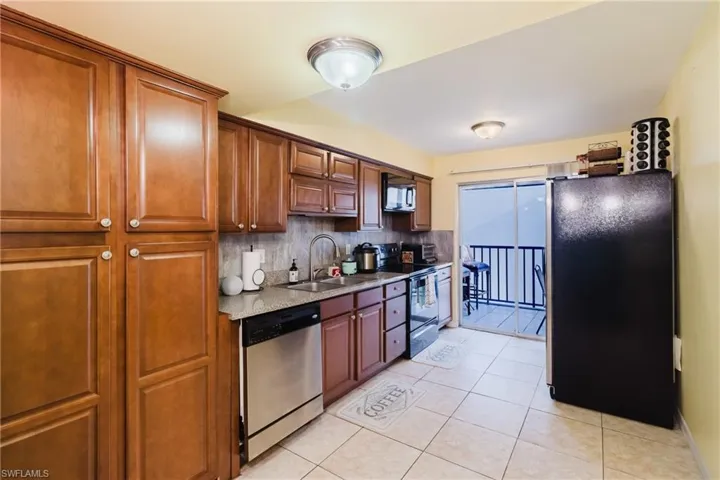 Kitchen with electric stove, a sink, freestanding refrigerator, decorative backsplash, and dishwasher
