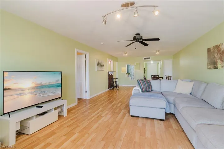 Living room with visible vents, baseboards, light wood-style flooring, and a ceiling fan