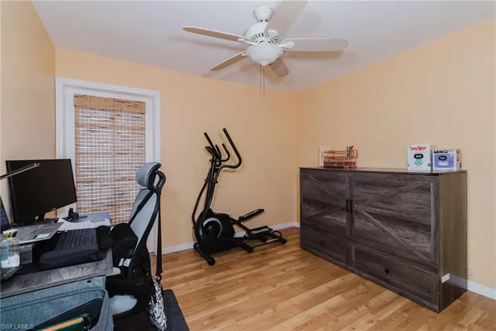 Workout room with ceiling fan, baseboards, and light wood-style flooring