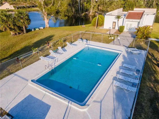 Pool with a patio area, a lawn, fence, and a water view
