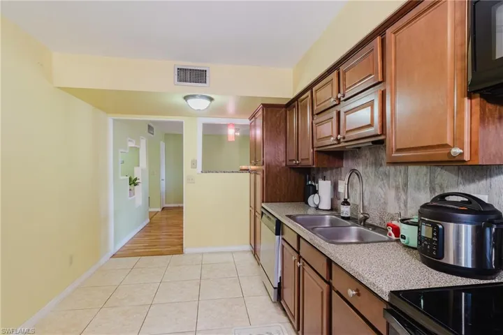 Kitchen with tasteful backsplash, visible vents, dishwasher, light tile patterned flooring, and a sink