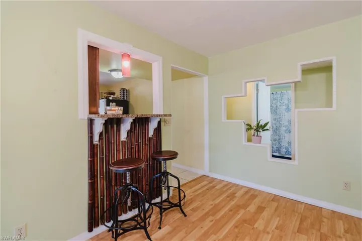 Bar with a dry bar, light wood-style flooring, and baseboards