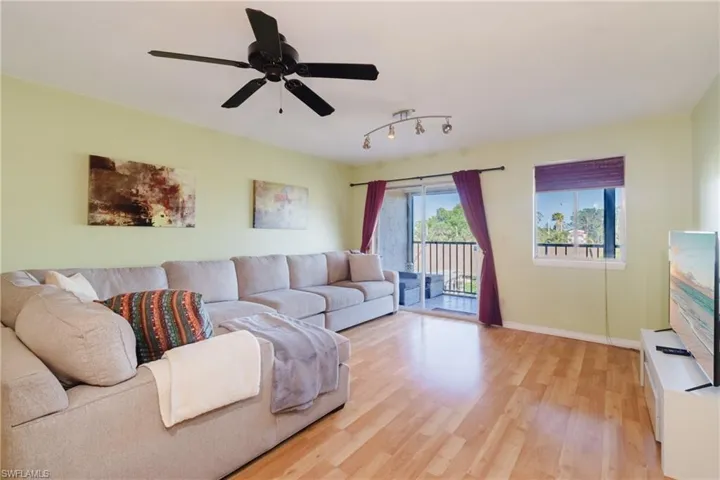 Living area with light wood finished floors, a ceiling fan, and baseboards