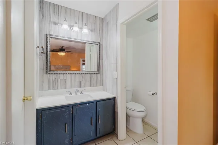 Bathroom with tile patterned floors, visible vents, toilet, and vanity