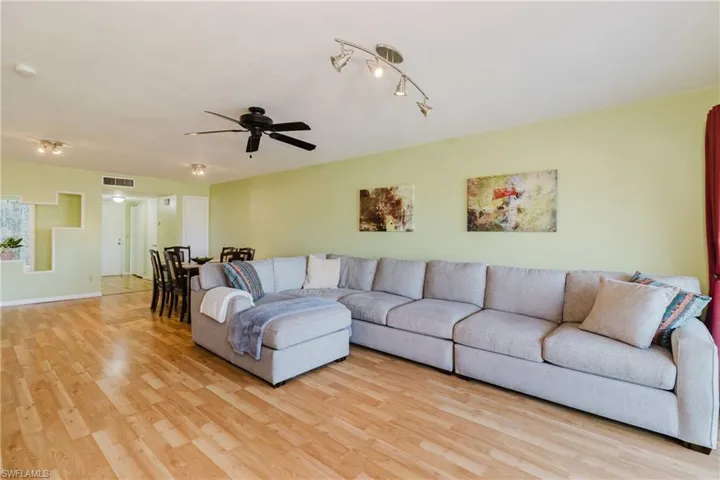 Living area with baseboards, visible vents, light wood finished floors, and ceiling fan