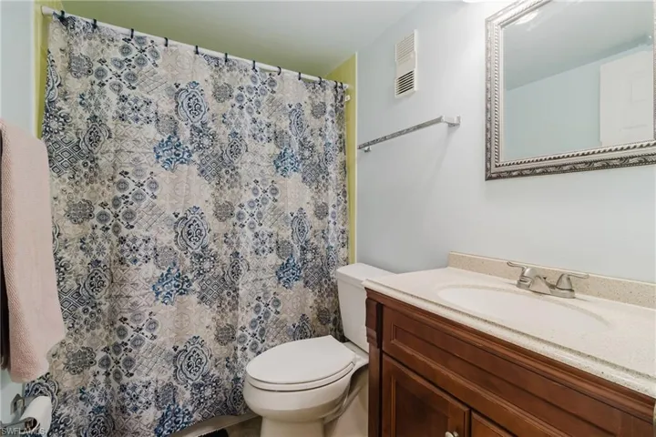 Bathroom featuring vanity, curtained shower, toilet, and visible vents