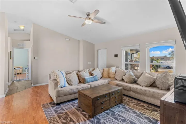 Living room with a ceiling fan, hardwood / wood-style floors, and lofted ceiling