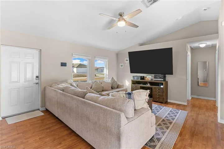 Living room with a ceiling fan, light wood-style floors, and lofted ceiling
