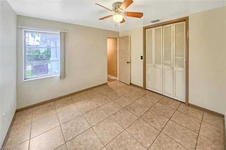 Unfurnished bedroom with ceiling fan, a closet, and light tile patterned floors