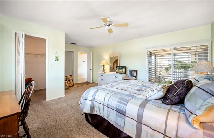 Carpeted bedroom with a spacious closet and a ceiling fan