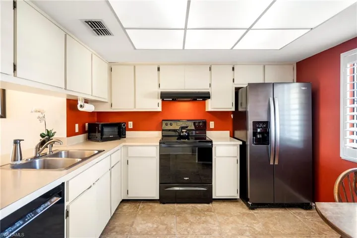 Kitchen featuring black appliances, light countertops, and cream cabinetry
