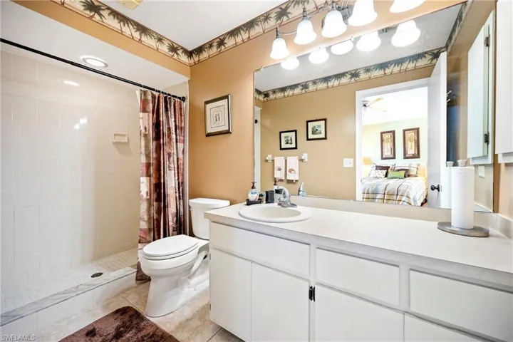 Bathroom with ensuite bathroom, a tile shower, vanity, and light tile patterned floors
