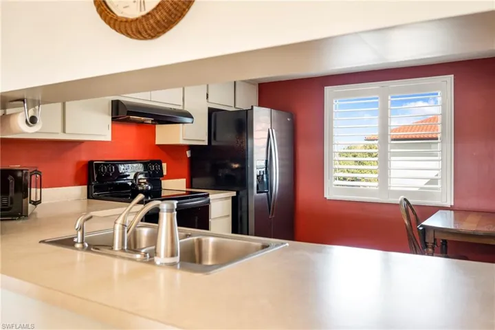 Kitchen with light countertops, electric range, white cabinetry, and stainless steel refrigerator