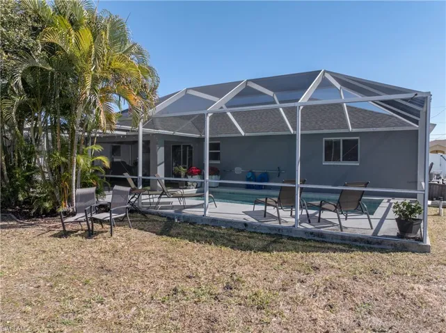 Back of property featuring a patio, a sunroom, a lanai, an outdoor pool, and a yard