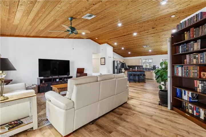 Living room with a high wood ceiling, light wood finished floors, a ceiling fan, and recessed lighting