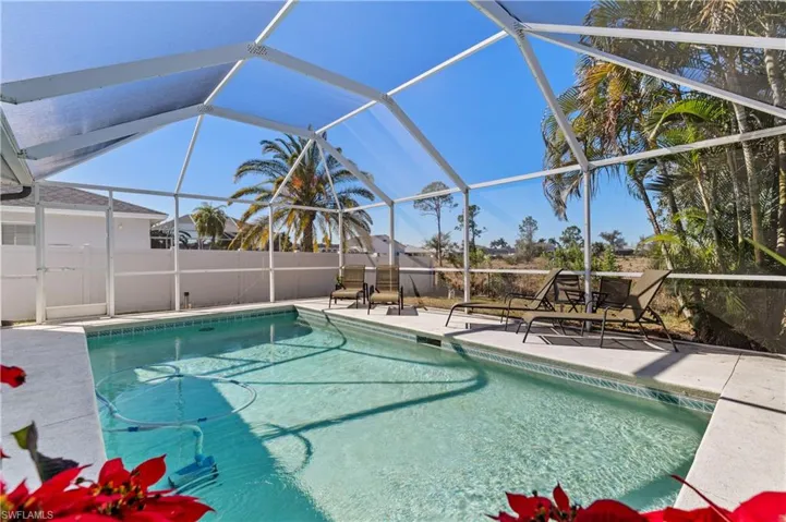 View of pool featuring glass enclosure, a sunroom, and patio surround