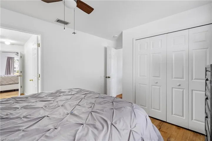 Bedroom with light wood-style floors, ceiling fan, and a closet